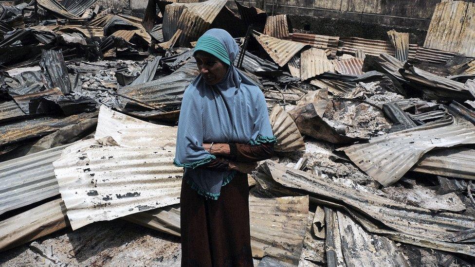 A woman stands beside the rubble that was once her stall at the market place in Fakfak, West Papua