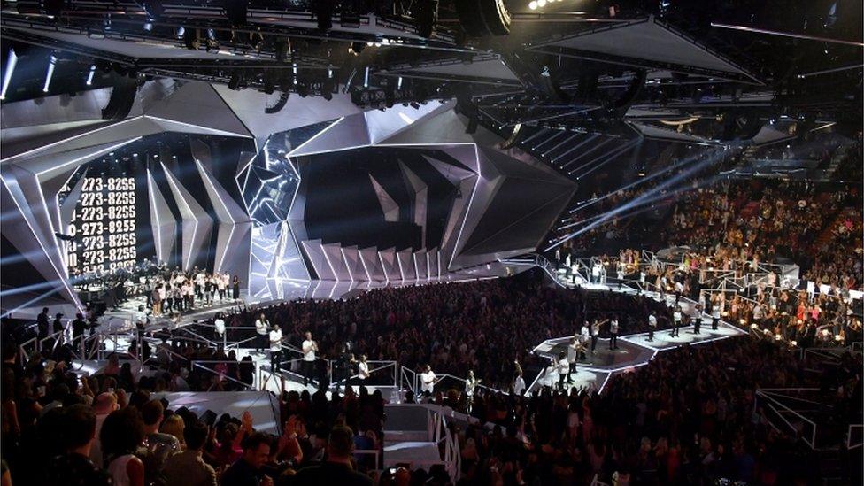 Logic, Alessia Cara, Khalid, and special guests perform onstage during the 2017 MTV Video Music Awards (A stage is shown lined with survivors and surrounded by crowds)