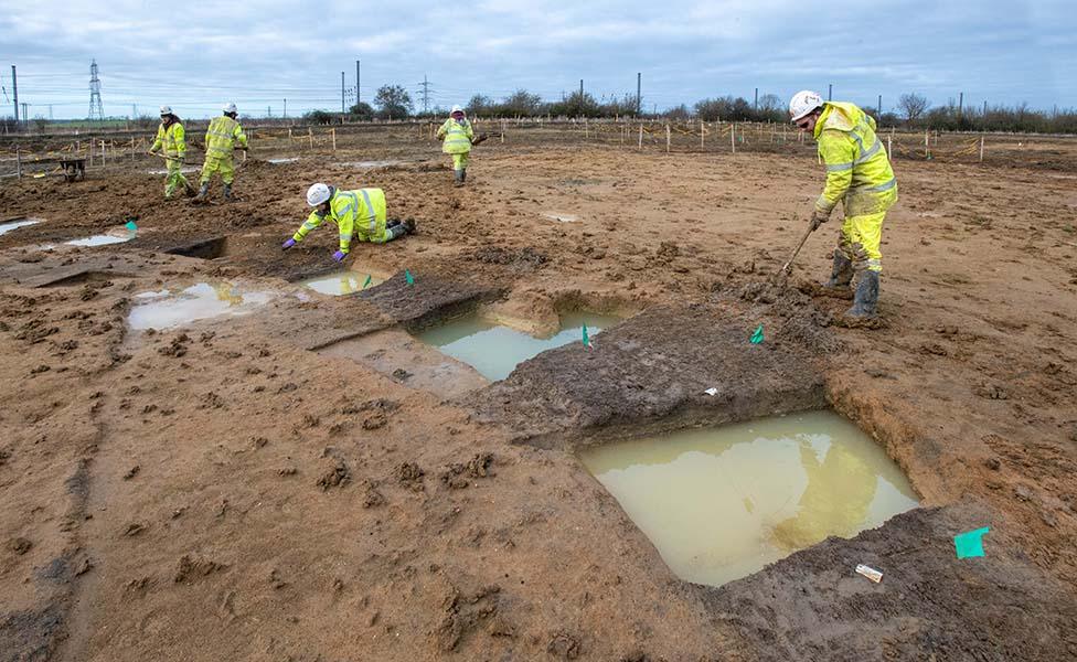 Archaeologists digging one of the Iron Age roundhouses at Field 44 on the A428