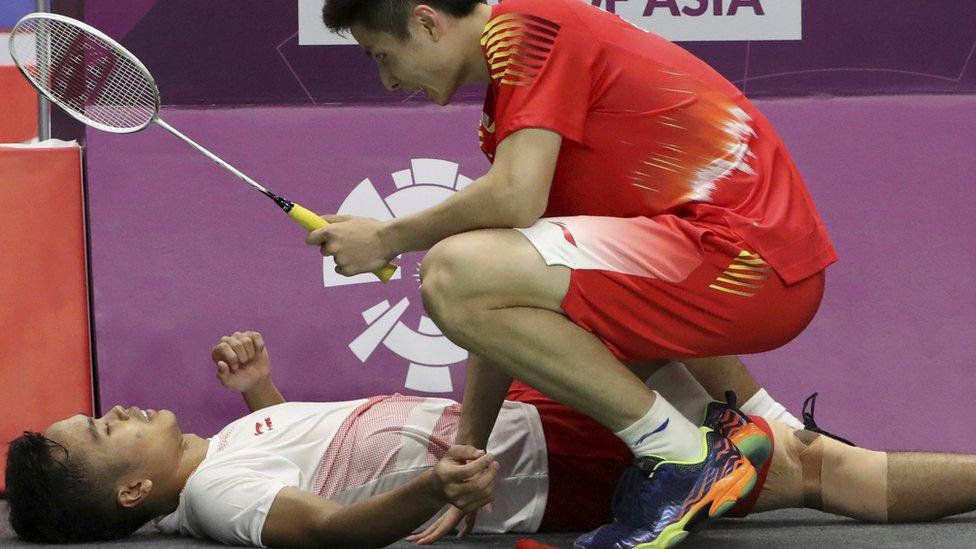 Pebulu tangkis tunggal putra Cina Shi Yuqi (kanan) menghampiri pebulu tangkis tunggal putra Indonesia Anthony Sinisuka Ginting (kiri) yang mengalami cedera saat set ketiga pada babak final beregu putra Asian Games 2018 di Istora Senayan, Jakarta, Rabu (22/8).