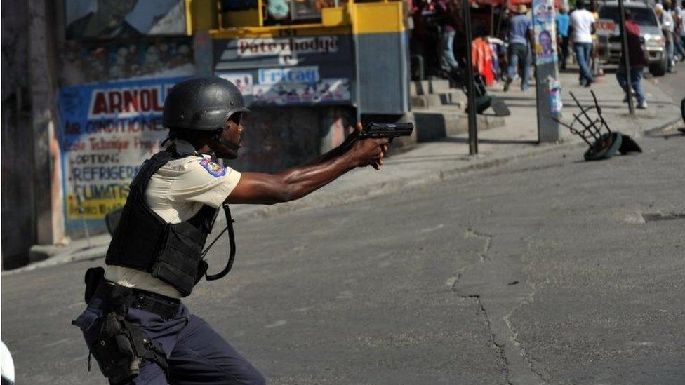 A Haitian policeman aims his gun during clashes with demonstrators in Port-au-Prince on 24 November, 2015.