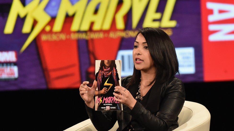 Sana Amanat holding up a Ms Marvel comic