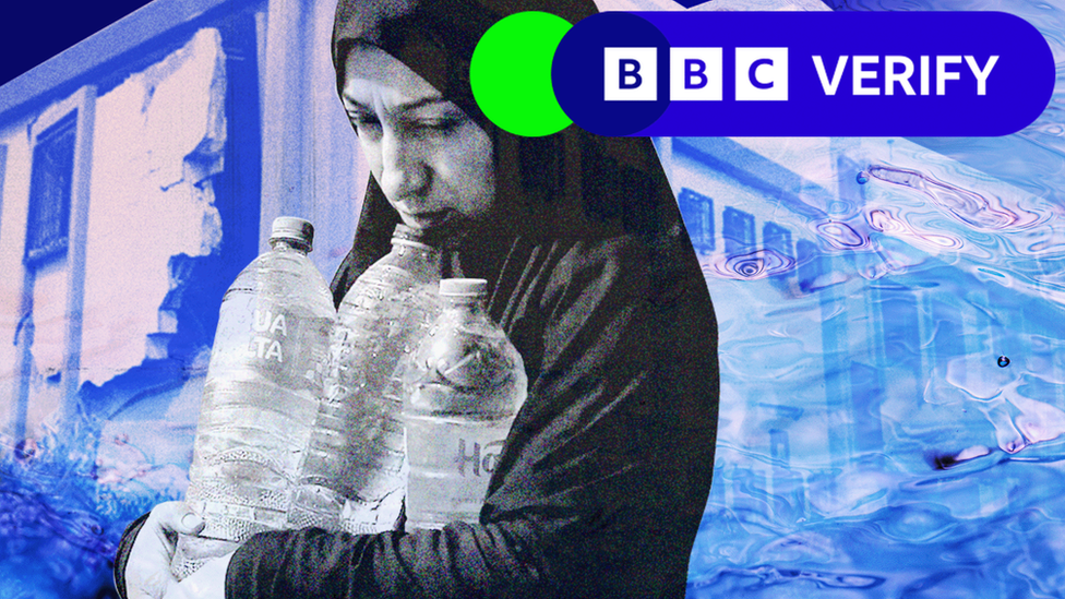 A woman carrying three plastic bottles of water