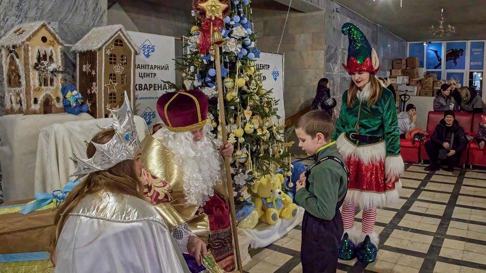 Ukrainian volunteers dressed as St. Nicolas and Snow Maiden perform with local children during the celebration of St. Nicolas day