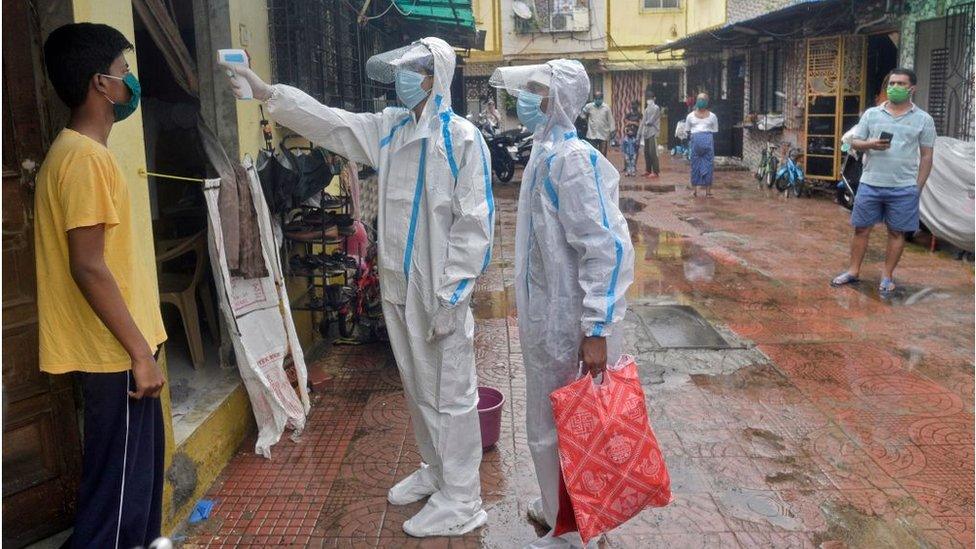 Health care staff check the temperature of a Mumbai resident