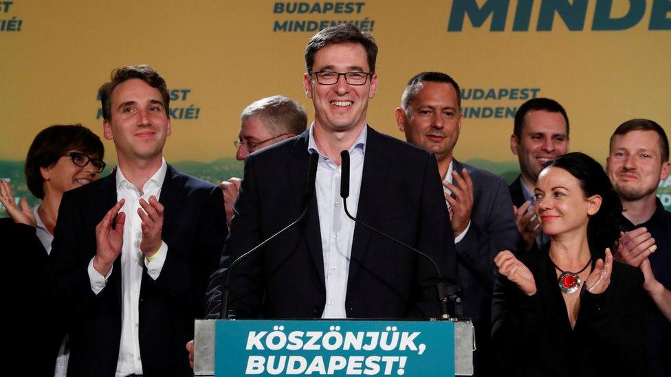 Newly elected Budapest mayor Gergely Karacsony stands smiling at a podium following his win