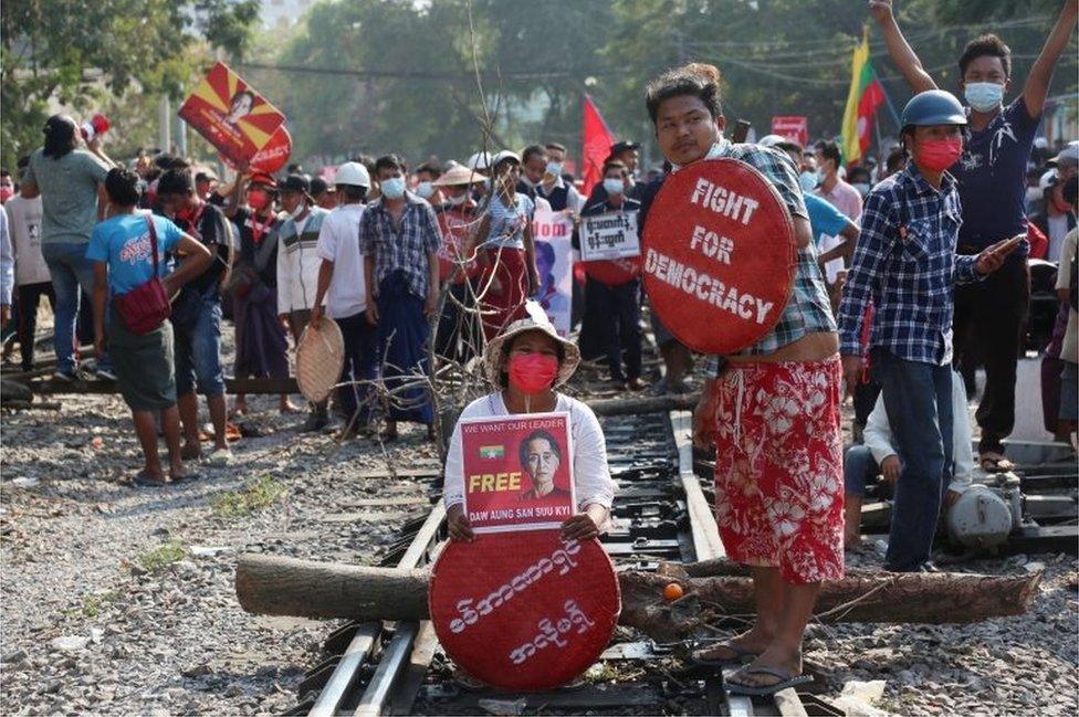 Demonstrators holding placards calling for the release of detained Myanmar"s State Counselor Aung San Suu Kyi block railway tracks during a protest against the military coup in Mandalay, Myanmar, 17 February 2021.