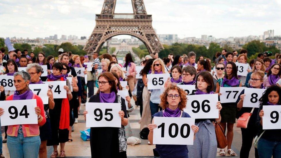 Women gathered in front of the Eiffel tower holding up numbers to represent the 101 femicides in France this year