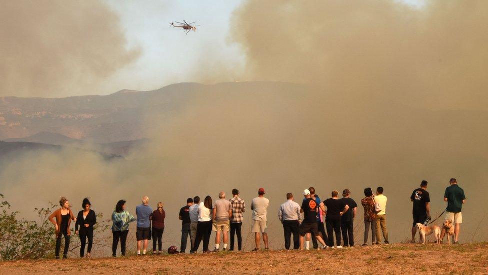 People watching helicopter dropping water