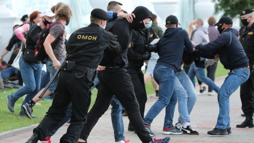 Police officers wearing protective face masks detain protesters during a rally in Minsk, Belarus