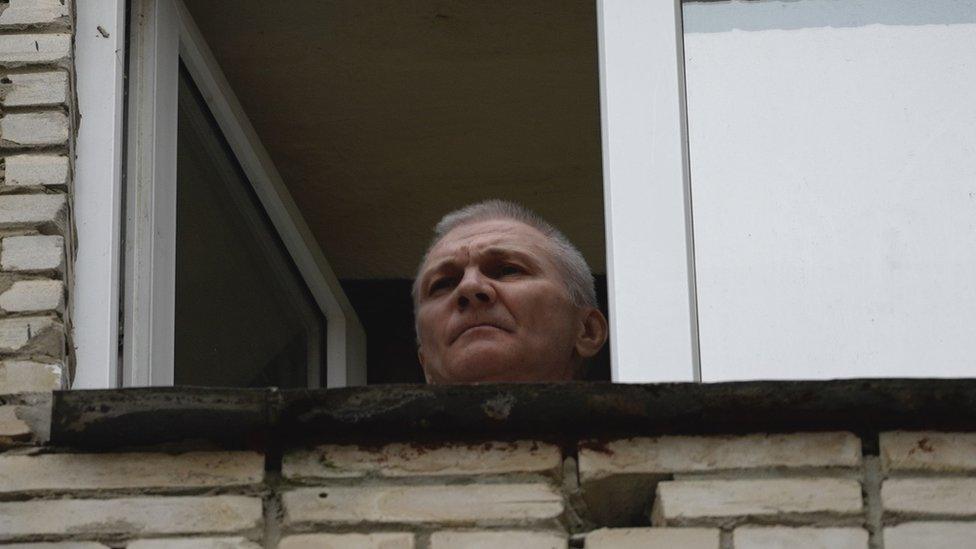 Alexei Moskalev appears at a window of the building where he is being held under house arrest