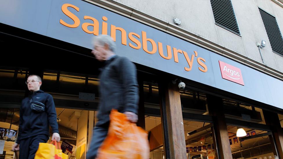 Men walk past Sainsbury's and Argos