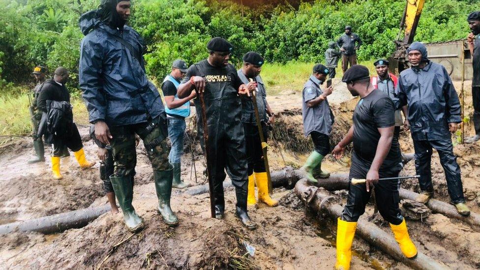 Security men stand around an oil pipeline