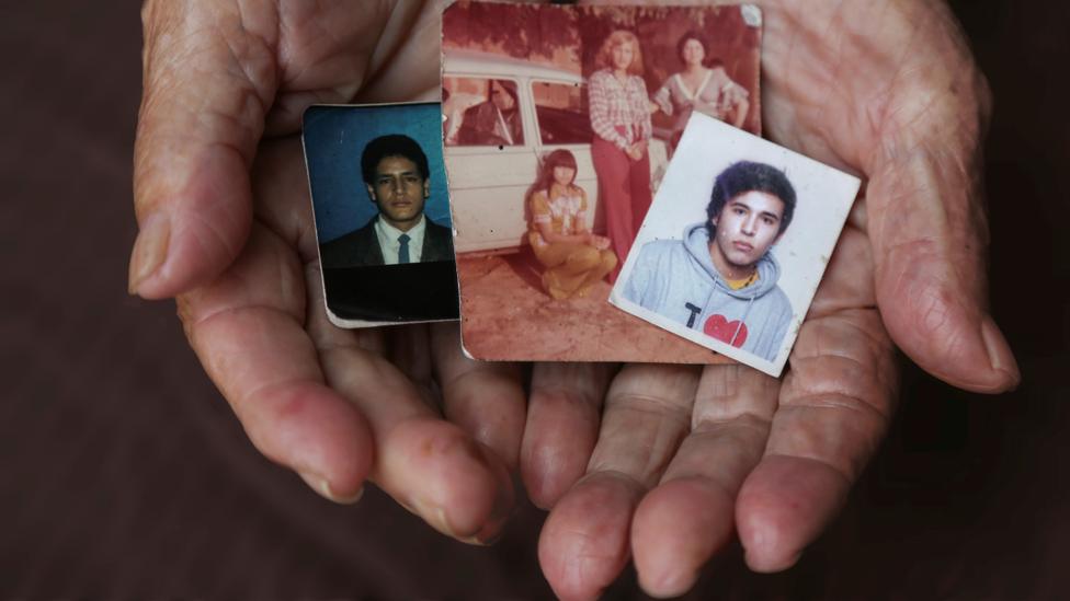 A close-up of María Teresa Jimenez's hands holding pictures of her children