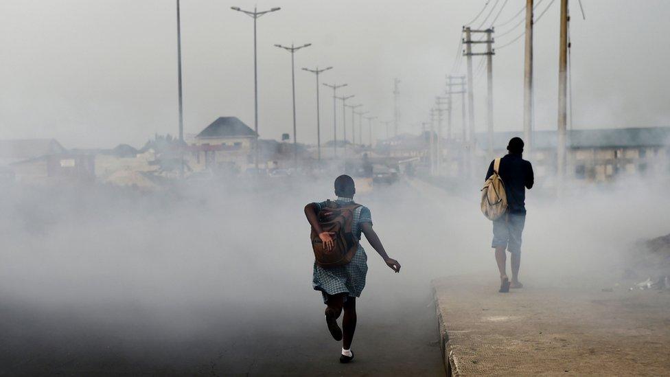 A schoolgirl walks past smoke emitted from a dump in the city of Port Harcourt.