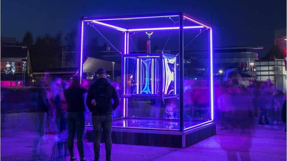 People viewing an installation of a 3D illuminated cube