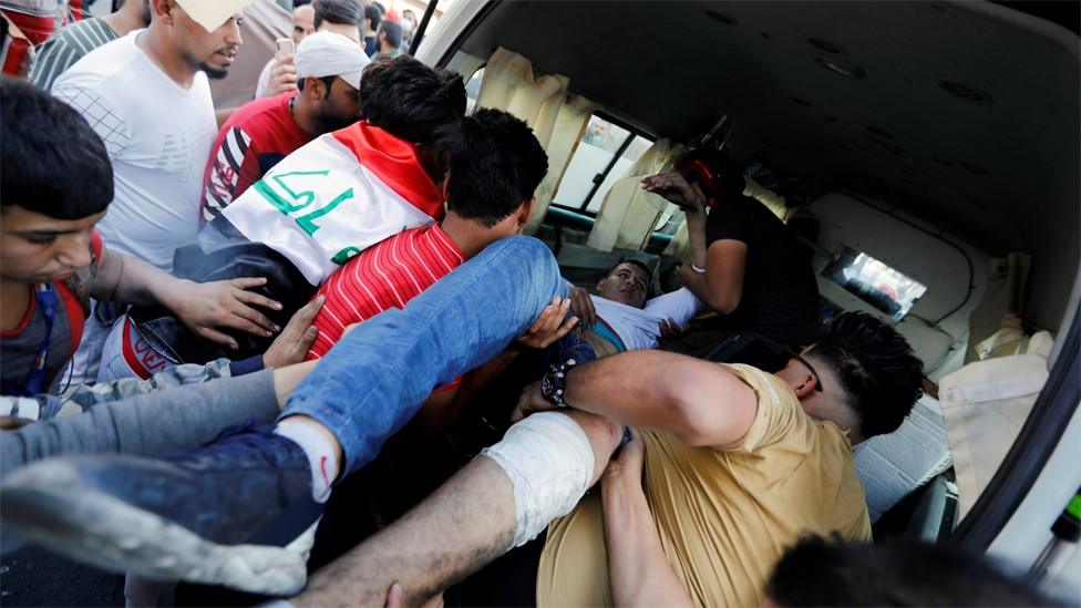 Protesters carry a wounded man during a demonstration in Baghdad, Iraq (11 November 2019)