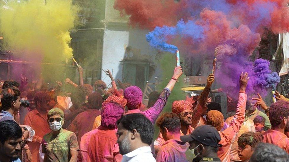 Revellers smeared in coloured powder dance during the Holi celebrations, the Hindu spring festival of colours, in Hyderabad on March 17, 2022.