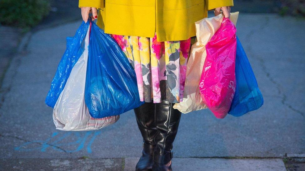 a woman carrying shopping in plastic carrier bags