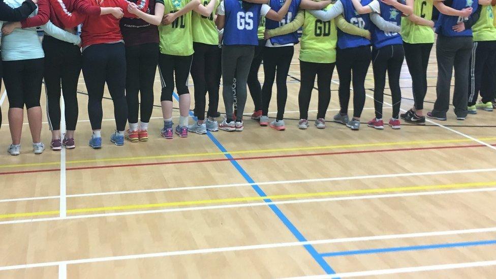 The team in a line from behind wearing netball bibs