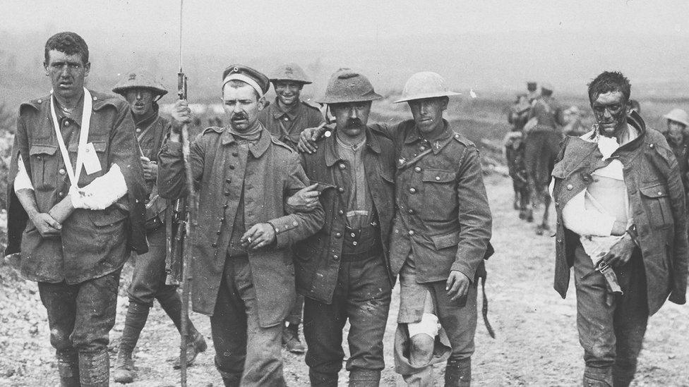 a wounded German prisoner of war assisting wounded British soldiers on the Somme front