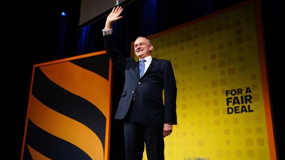 Liberal Democrat leader Sir Ed Davey on stage during his speech to his party's conference. He is seen waving to the crowd.