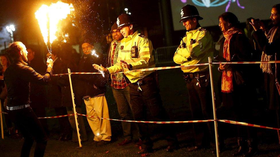 A Leicestershire Police officer pretends to warm his hands on a fire eater's sticks before the switching on of Diwali lights in Leicester