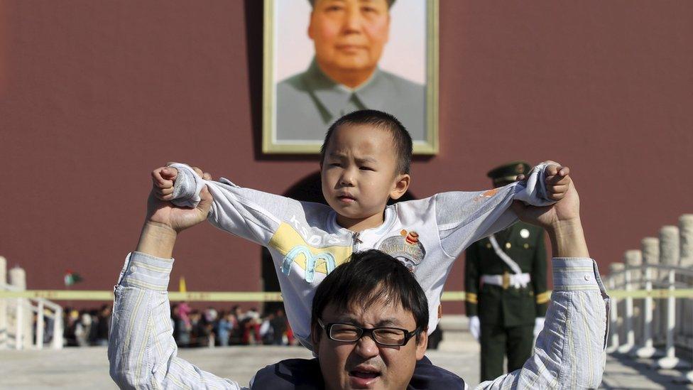 A boy sits on his father's shoulders as they pose for a photograph in front of the giant portrait of late Chinese chairman Mao Zedong on the Tiananmen Gate, in Beijing, China, October 2, 2011.