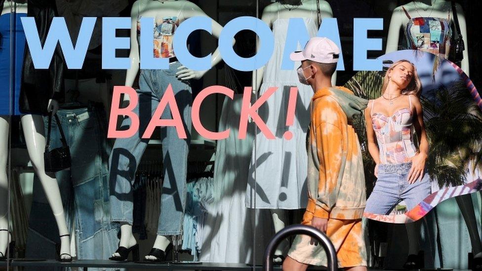 A pedestrian wearing a face mask walks past a storefront in Auckland, New Zealand.