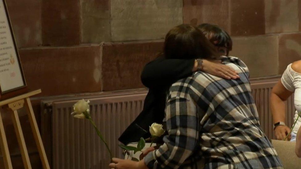 Bereaved mothers hug at the service