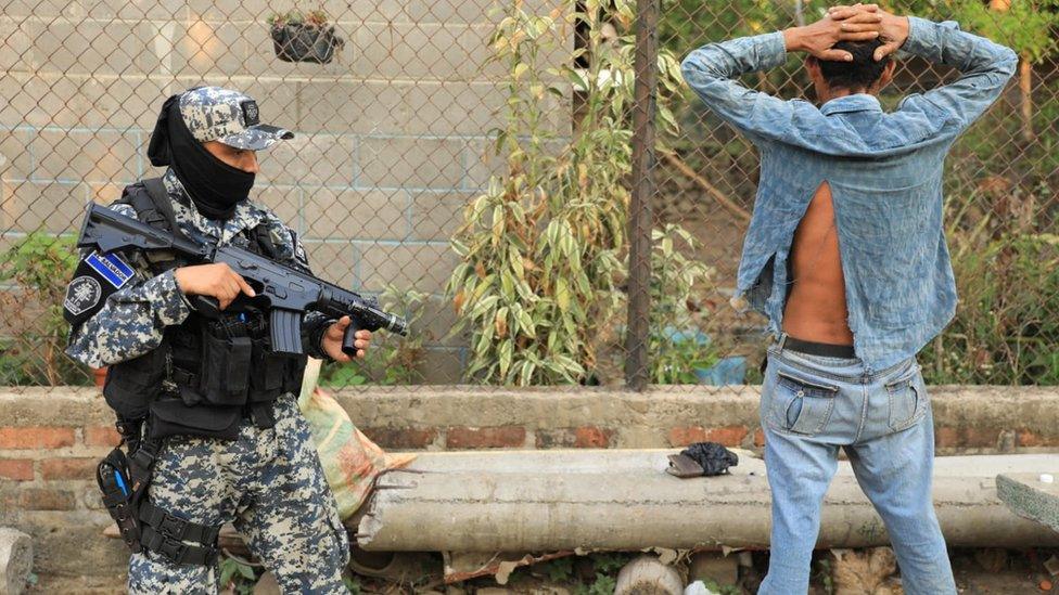 Police officer watches a man in a rural area of Nueva Concepcion after El Salvador's President Nayib Bukele announced the deployment of more than 5,000 security forces to the area after a policeman was killed in a gang attack, in Nueva Concepcion, El Salvador in this handout distributed to Reuters, May 17, 2023