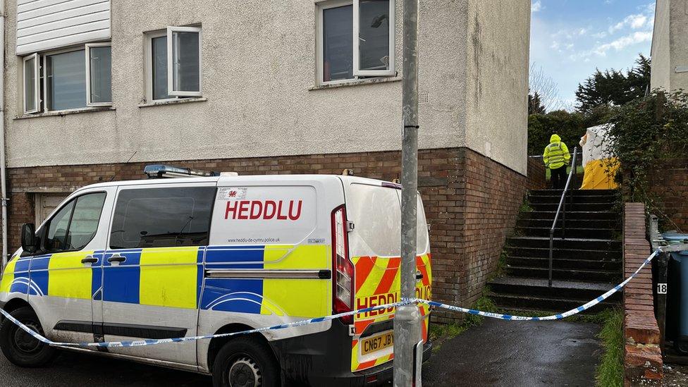 House with police van and police tape out front and forensics tent