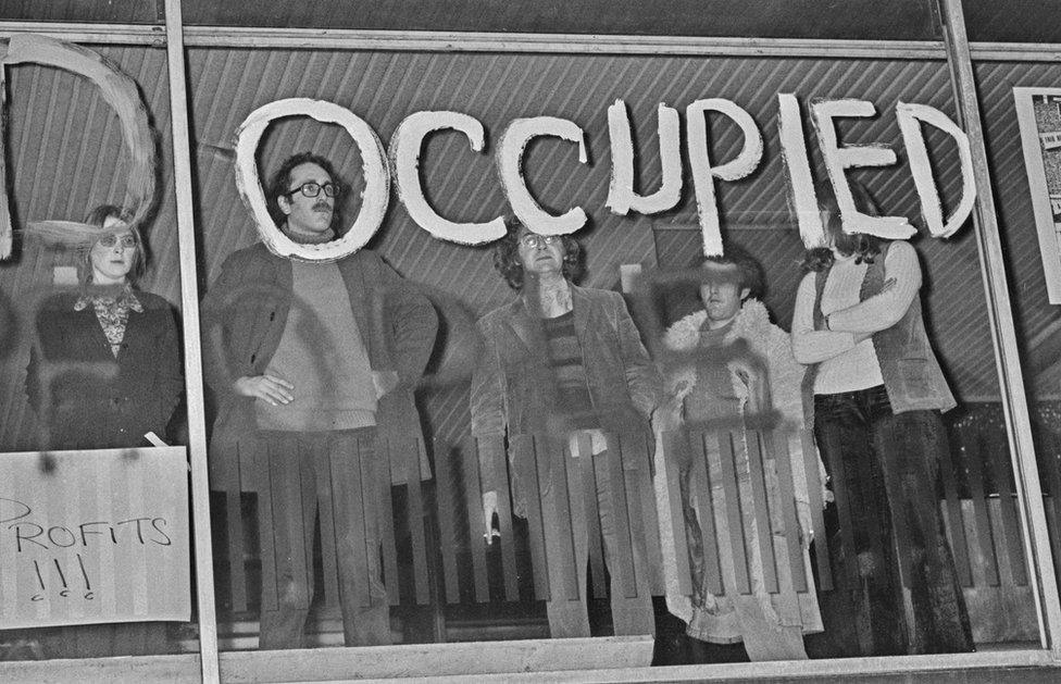 Black and white photo of protesters occupying the Centre Point building with "occupied" daubed over the window