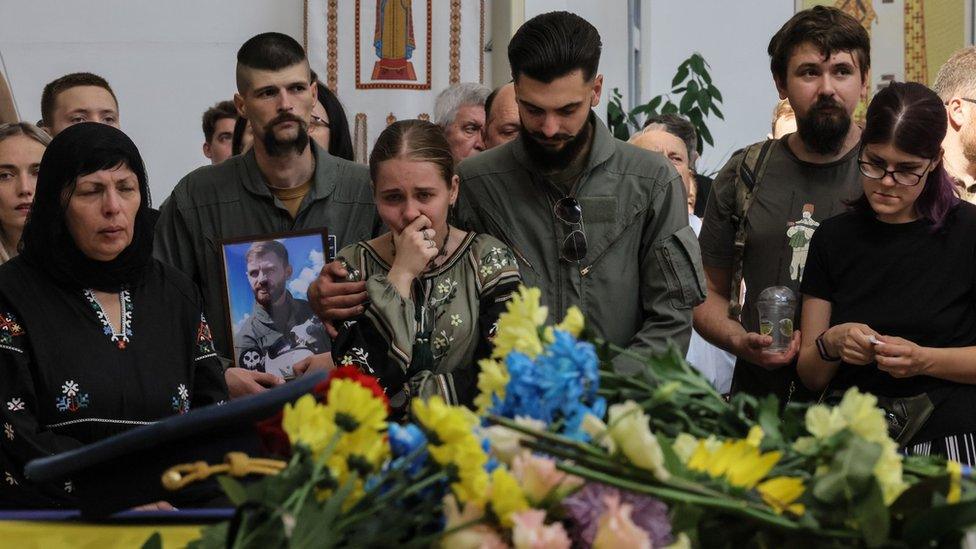 A man holds a photo of Ukrainian fighter pilot Andriy Pilshchykov during his funeral ceremony at a cathedral in Kyiv. Photo: 29 August 2023