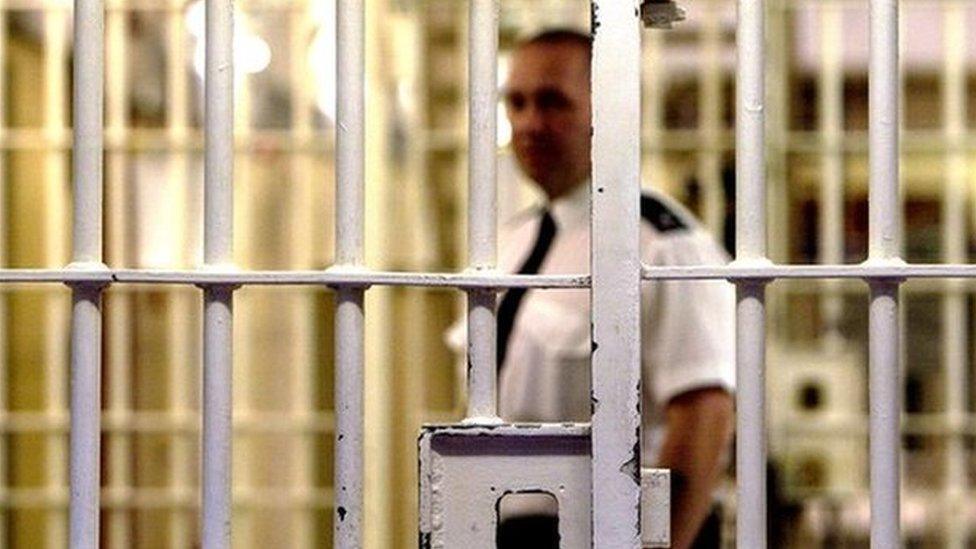 Prison officer seen through bars