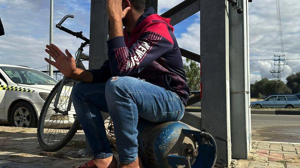 A young man sitting on a cooking gas cylinder in Deir al-Balah