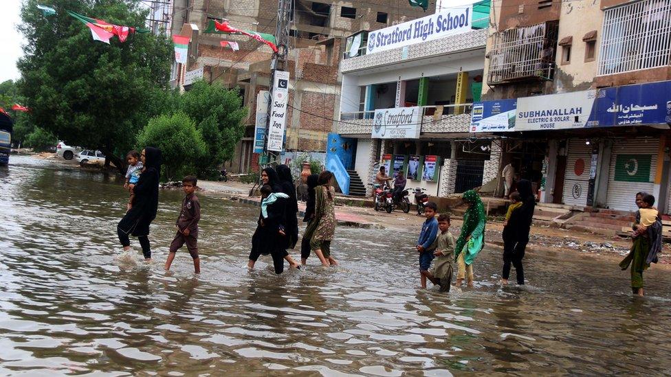 Women and children cross a flooded street in Karachi