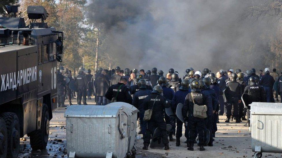 Bulgarian riot police stand near garbage bins during clashes in the migrants reception centre in the town of Harmanli