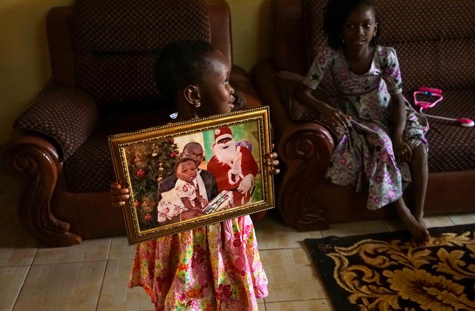 Girl holding up a picture of her with Father Christmas