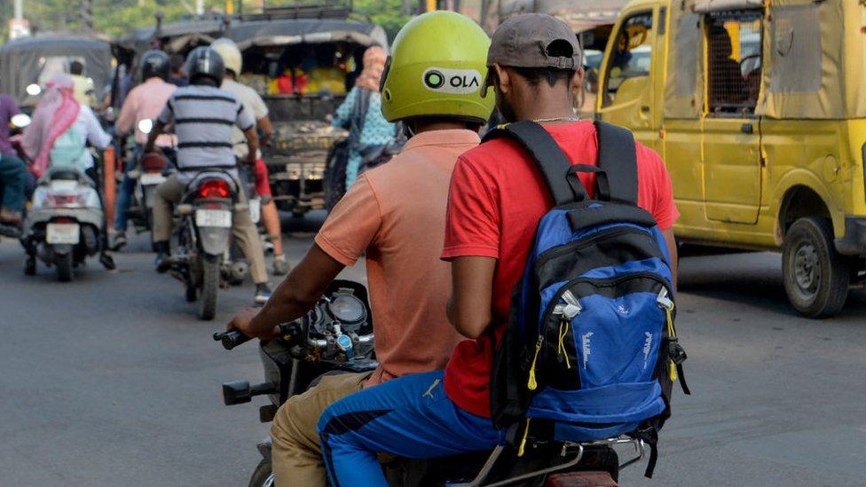 In this photograph taken on September 12, 2019, an Ola motorcyclist transports a passenger in Amritsar