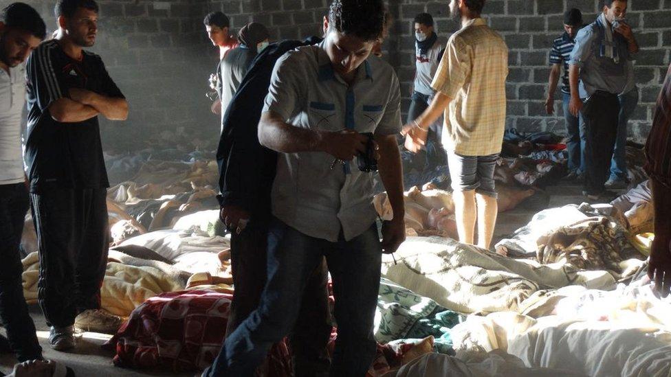 People look at the bodies of people killed in a sarin nerve agent attack in the rebel-held Ghouta region of Damascus on 21 August 2013