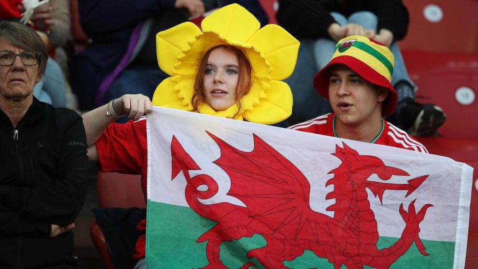 woman with welsh flag wearing daffodil hat