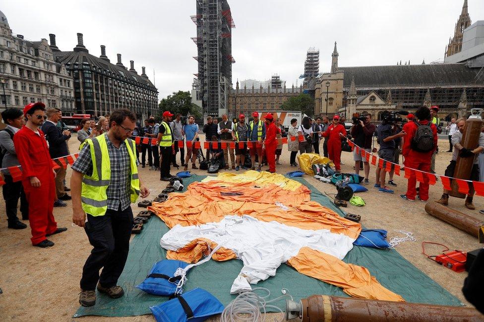 Demonstrators prepare to inflate a blimp portraying US President Donald Trump, in Parliament Square, London