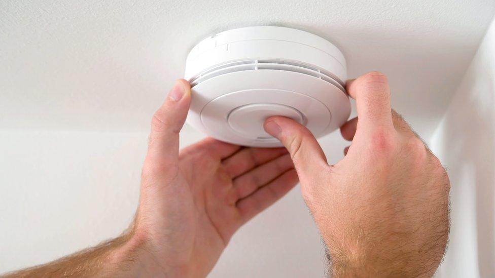 A man tests a smoke alarm