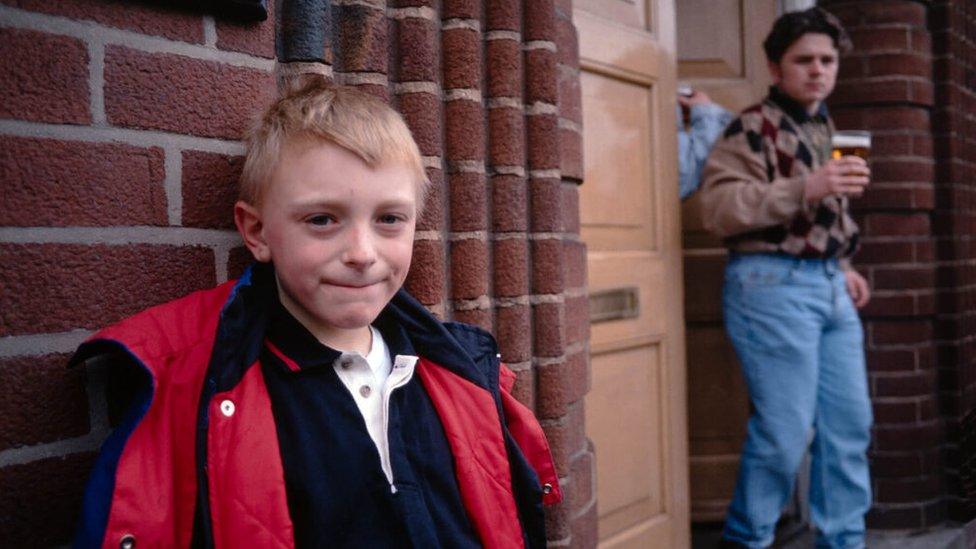 A boy stands outside a pub