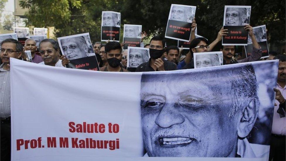 Indian writers and cultural activists wear black cloth over their mouths as they carry placards and a banner during a silent protest march outside Sahitya Akademi or National Academy of Letters, in New Delhi, India, Friday, Oct. 23, 2015.