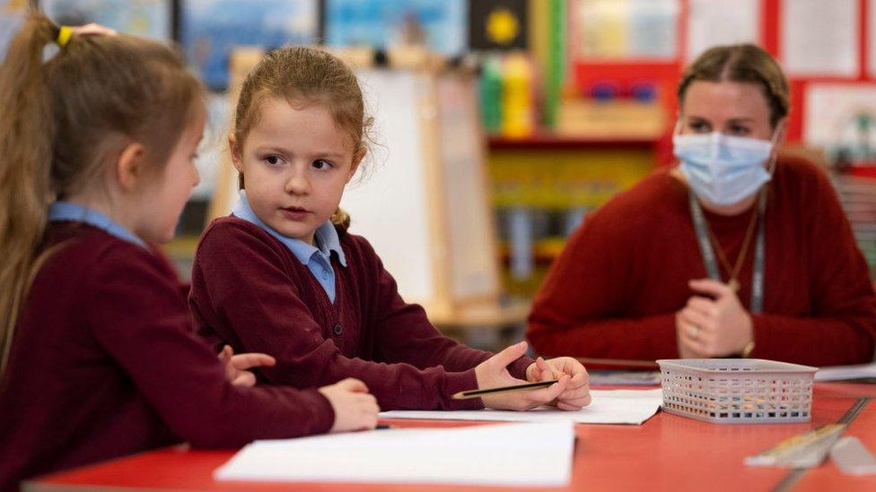 Teacher wears mask with two young pupils