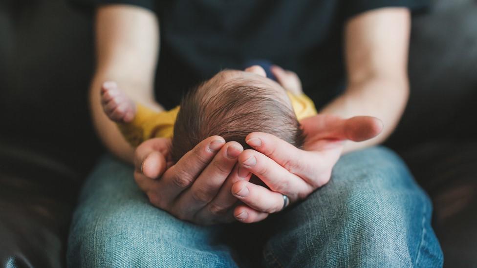 Man cradles a newborn child