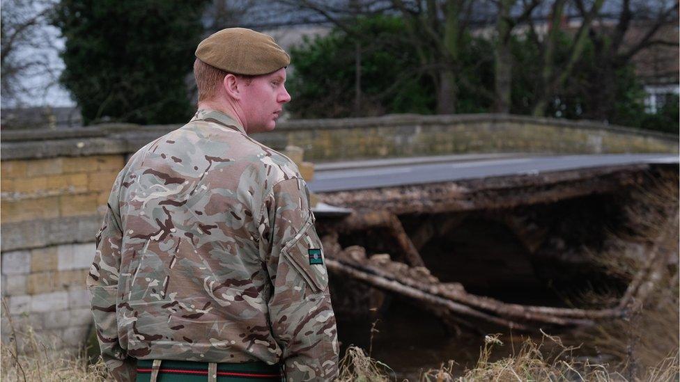 A soldier from 2 Battalion The Yorkshire Regiment stands on the riverbanks at the site of the collapsed bridge over the River Wharfe in Tadcaster