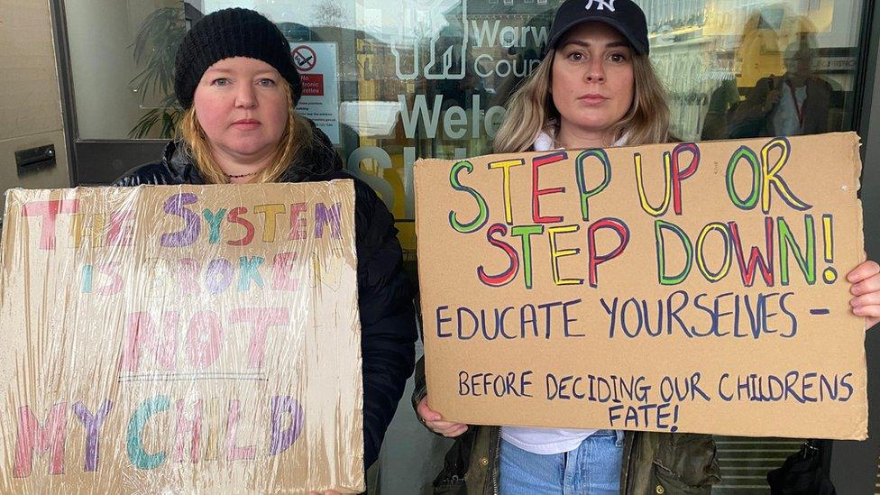 Two women with posters - one reads 'step up or step down - educate yourselves'